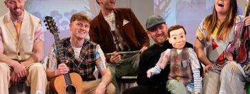 Group of young people one holding a puppet smiling