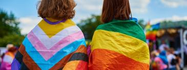 2 PEOPLE SITTING WITH FLAGS WRAPPED AROUND THEM. 