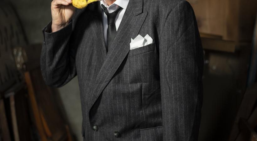 Image of man in a suit holding a banana to his ear.