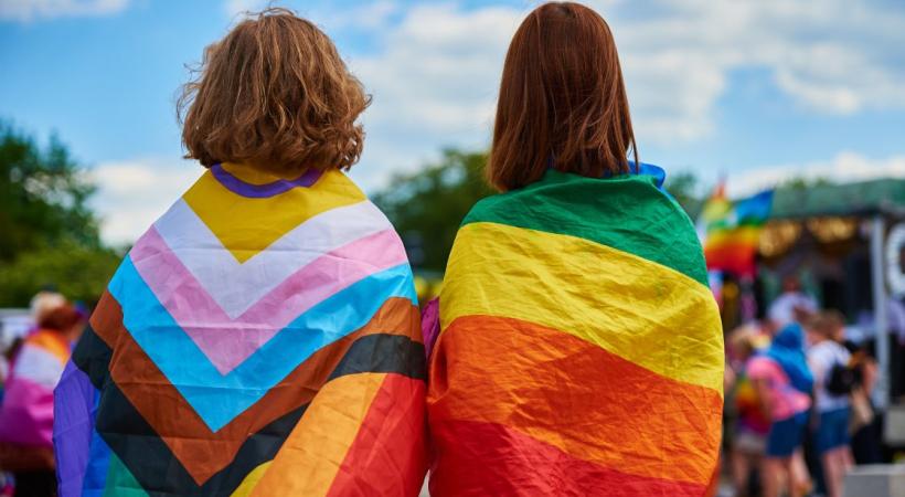 2 PEOPLE SITTING WITH FLAGS WRAPPED AROUND THEM. 