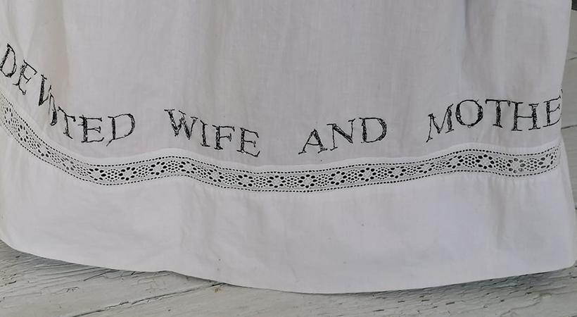 Hem of a dress with writing on it saying Devoted Wife and Mother